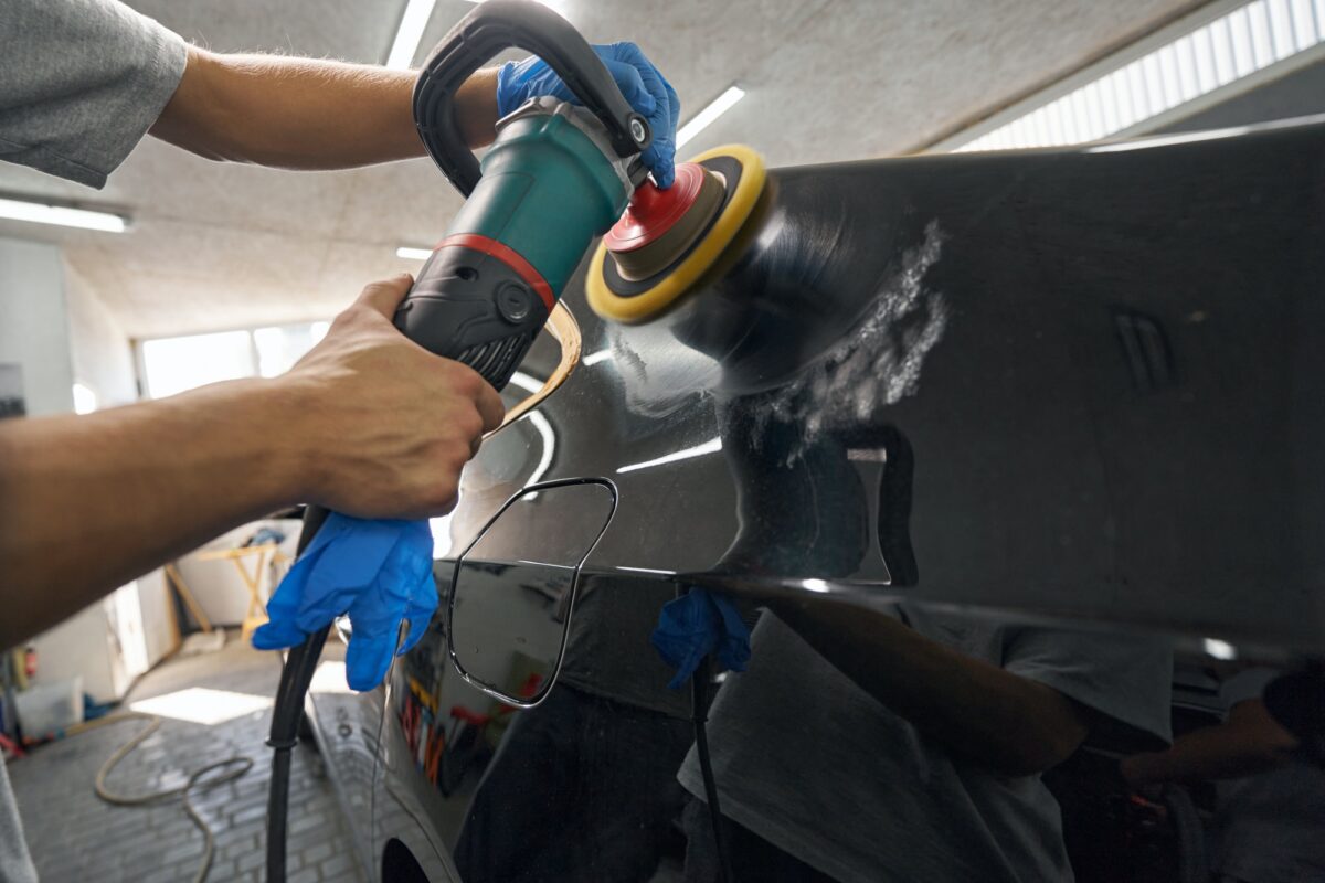 Car detailing studio worker polishing car paint and removing stratches